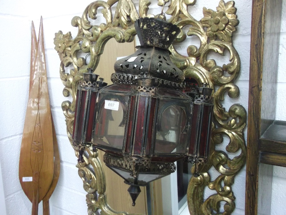 A metal Middle Eastern style hanging light having red and opaque glass