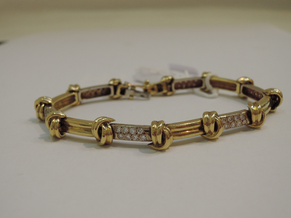 A white and yellow metal articulated bracelet marked 750 set with diamond chips and knot decoration