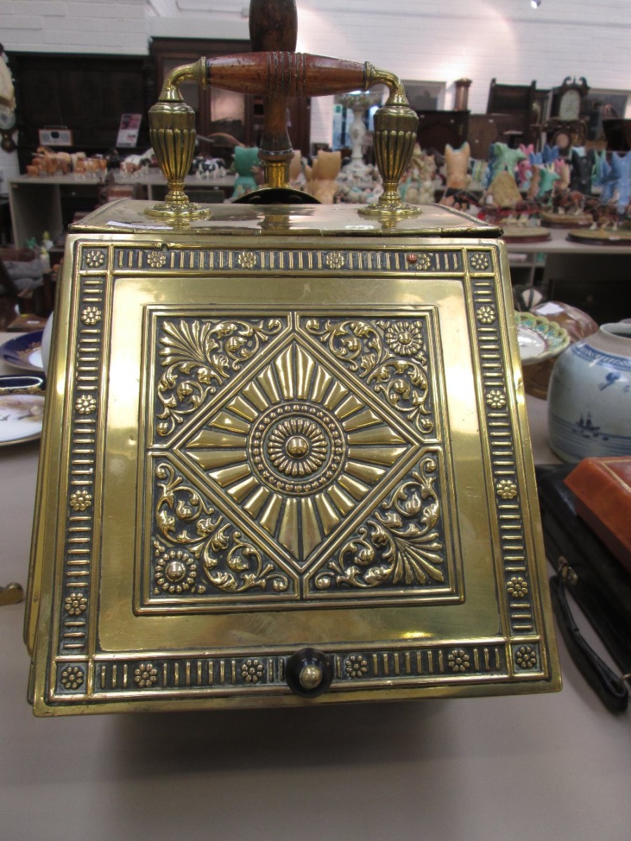 A late Victorian brass coal scuttle having embossed floral lid and bun feet