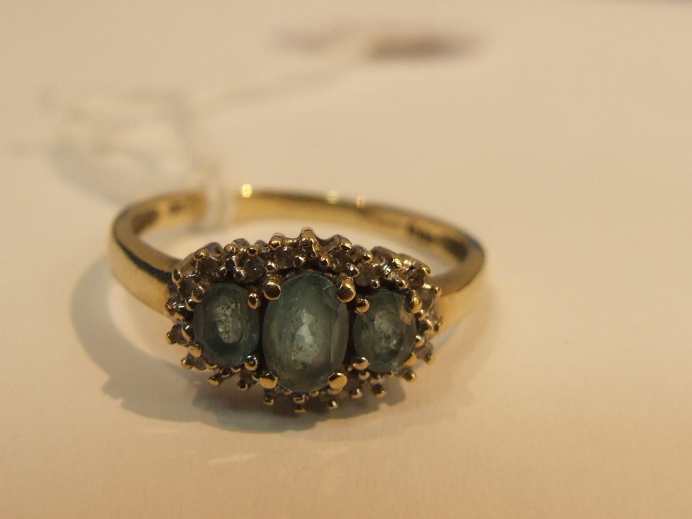 A ladies dress ring having three graduated oval topaz stones surrounded by diamond chips on a 9ct