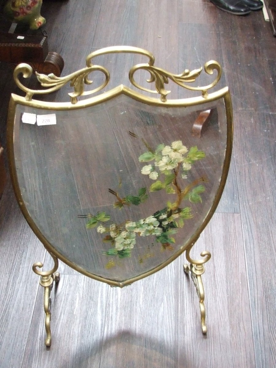 A Victorian brass frame firescreen of shield shape having painted mirror inset