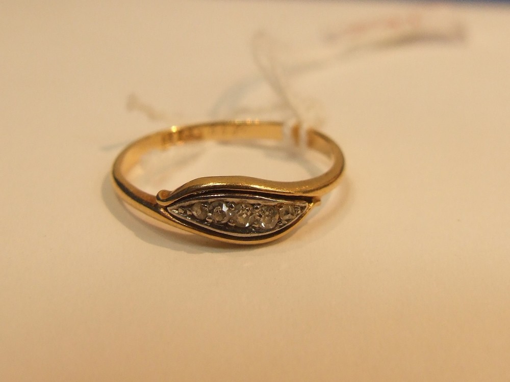 A ladies dress ring having 5 old cut graduated diamonds in a curved setting with yellow metal