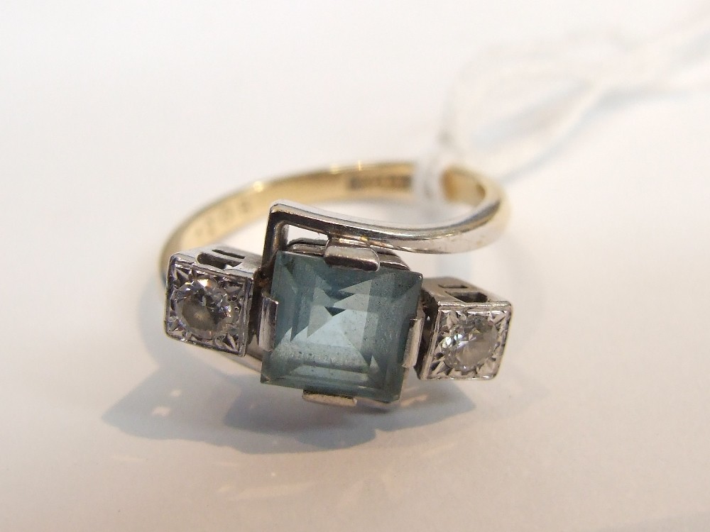 A ladies dress ring having central square blue topaz flanked by two diamonds in a geometric