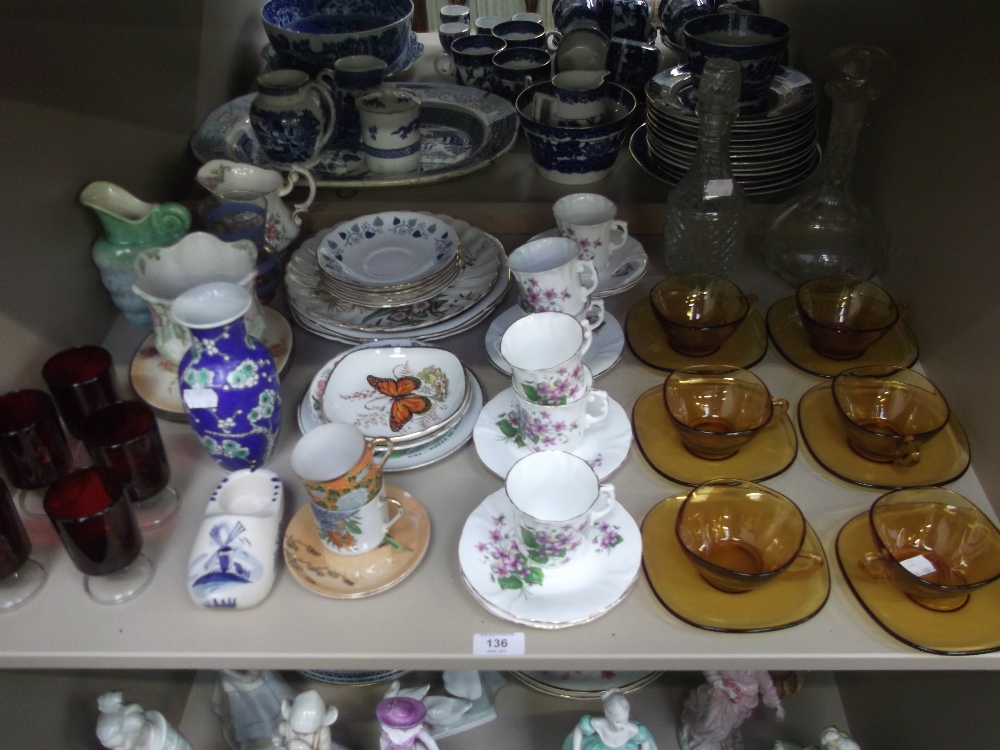 A shelf of decorative ceramics and glassware including a floral part tea set, French glass cups