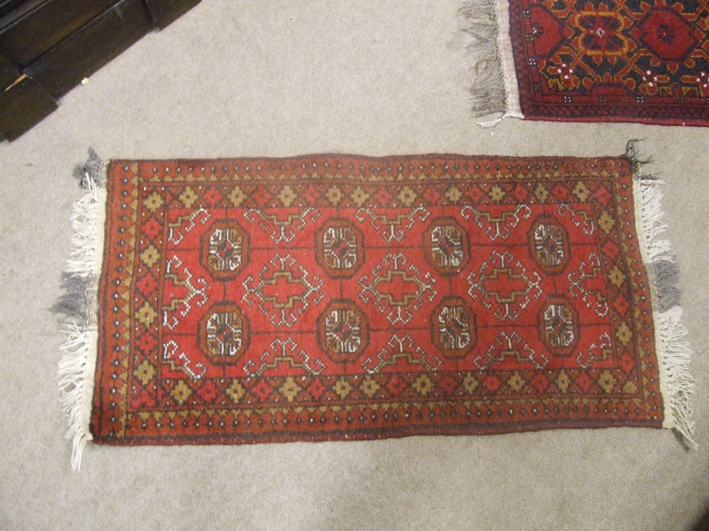 Five traditional style rugs, including Afghan design, all having red ground