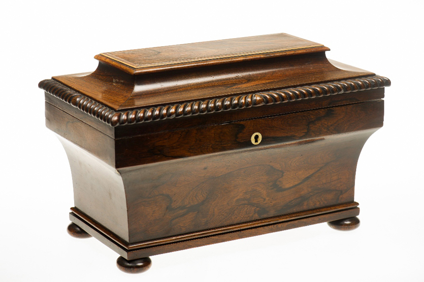 A REGENCY ROSEWOOD TEA CADDY, of sarcophagus form, the moulded top with stringing and gadrooned