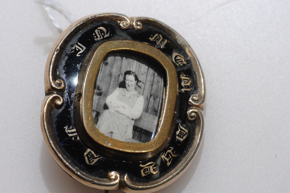 A 19th century yellow metal (unmarked) and black enamel mourning brooch, centred by a locket.