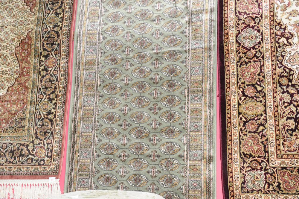 A Bokhara style runner with a green ground. 2.8m by 0.75m