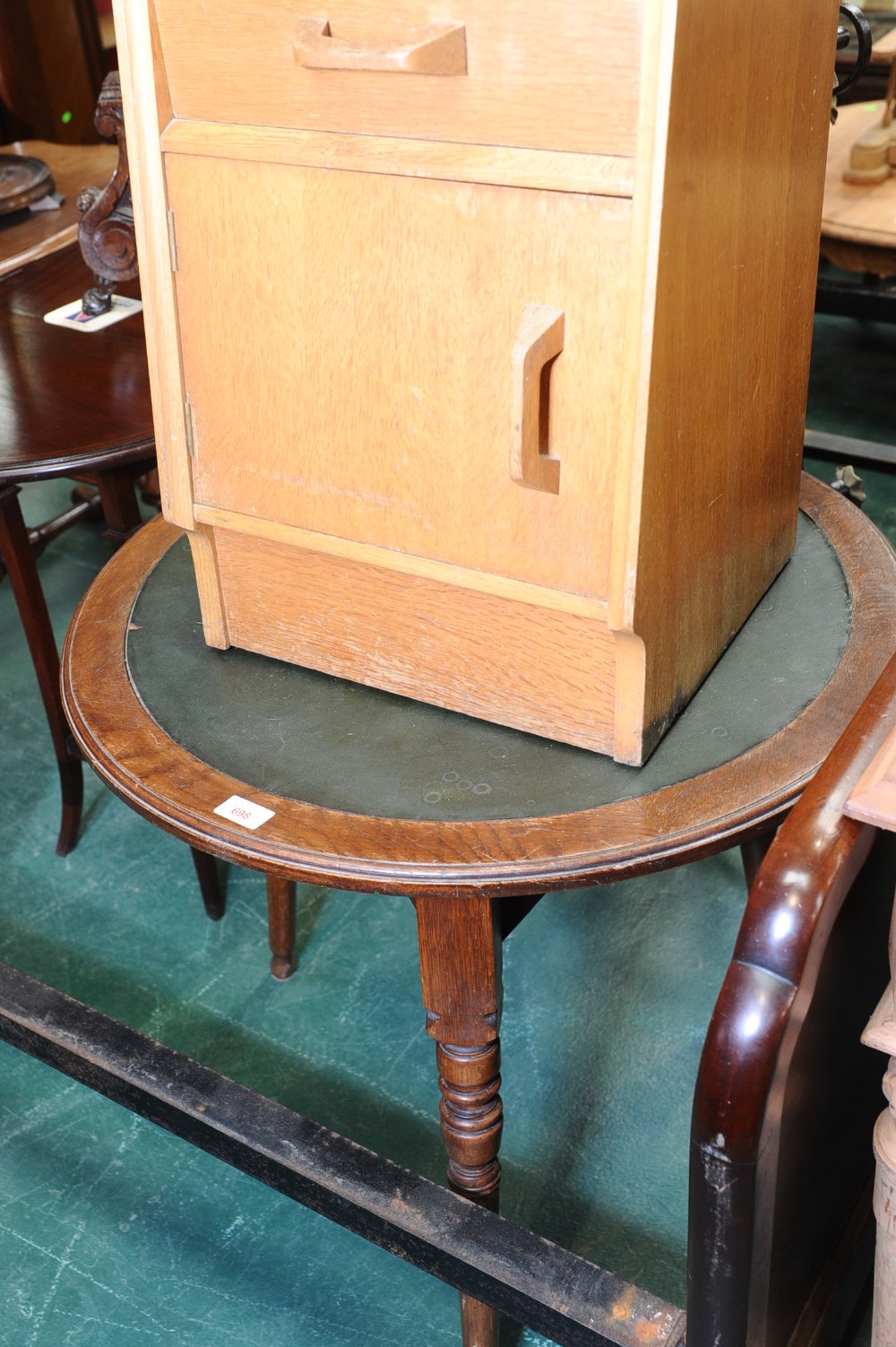A leather-inset oak circular occasional table in the manner of Liberty & Co., on three splayed legs