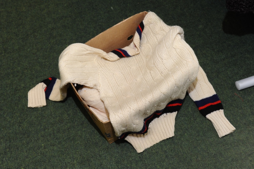 A box containing three vintage cricket sweaters