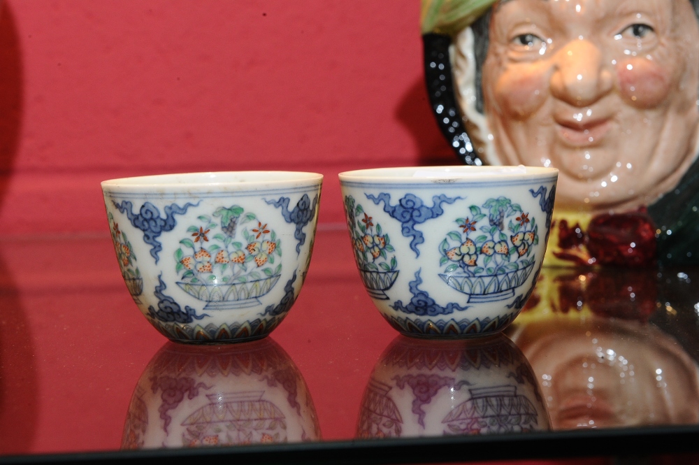 A pair of Chinese porcelain tea bowls, each decorated with baskets of fruit, seal mark.