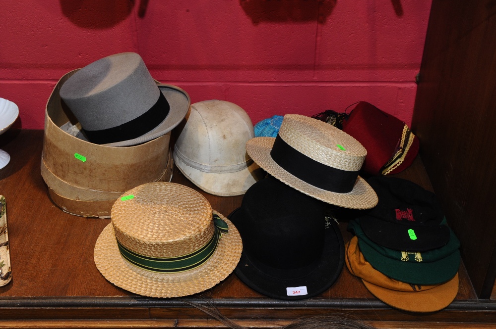 A group of hats inc. a grey top hat, a bowler hat, straw boaters, tassled smoking caps, sports caps,