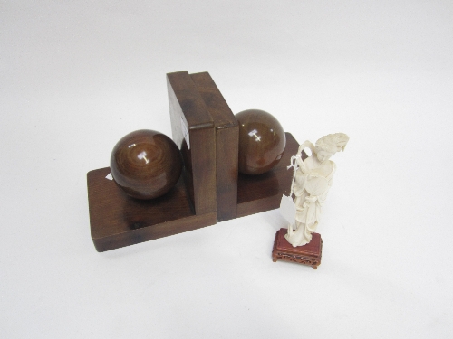 A PAIR OF STAINED WOOD BOOKENDS, each with a sphere, 16cm. and an ivorine figure, 18cm. (3)