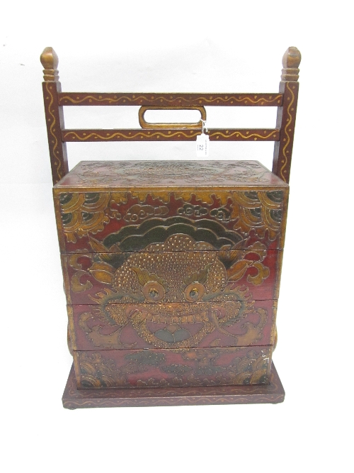 A MONGOLIAN RED LACQUER NEST OF BOXES, with overhead handle, painted with masks and scrollwork,