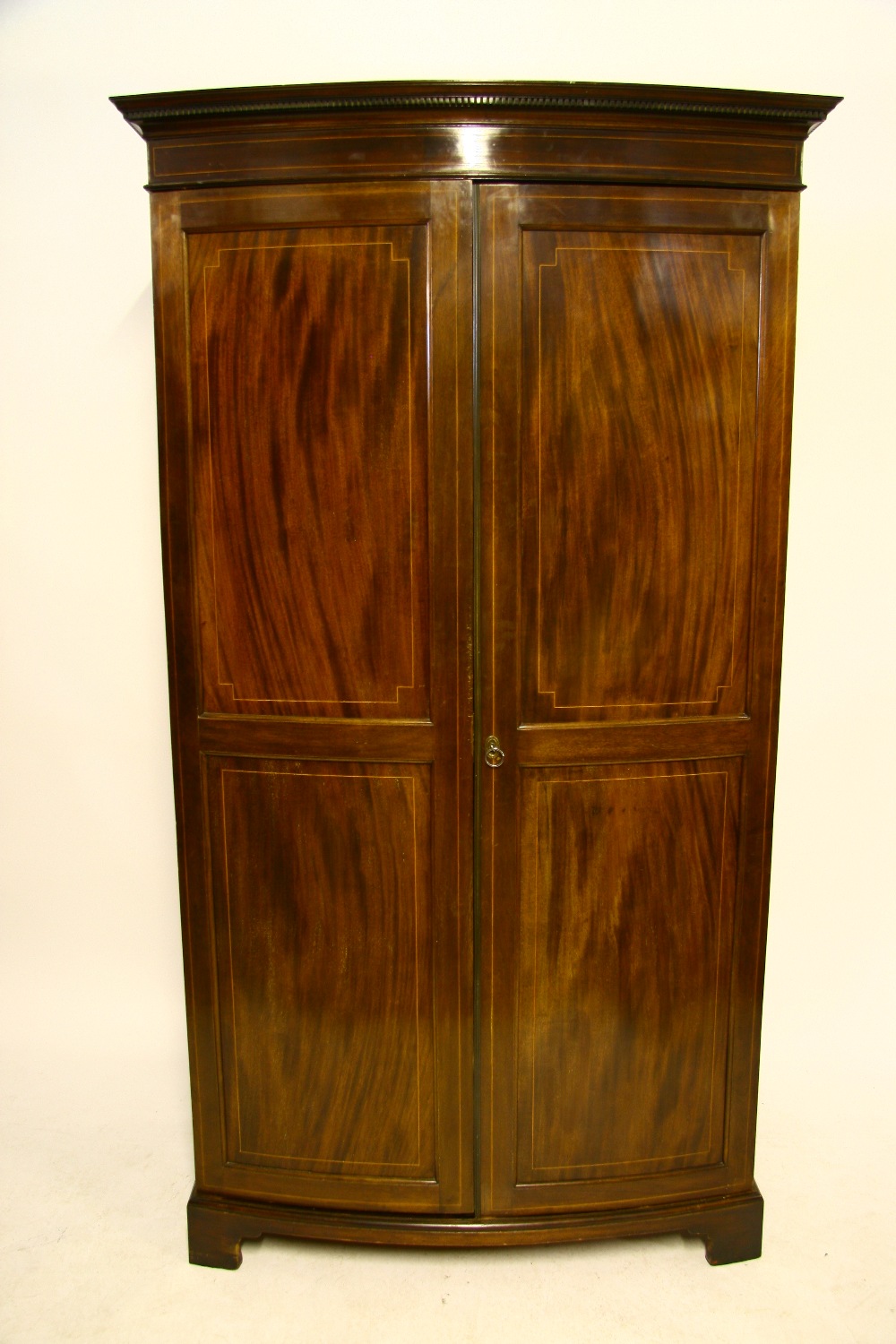 An Edwardian inlaid mahogany bow-front wardrobe enclosed pair of panel doors, on bracket feet; 42"