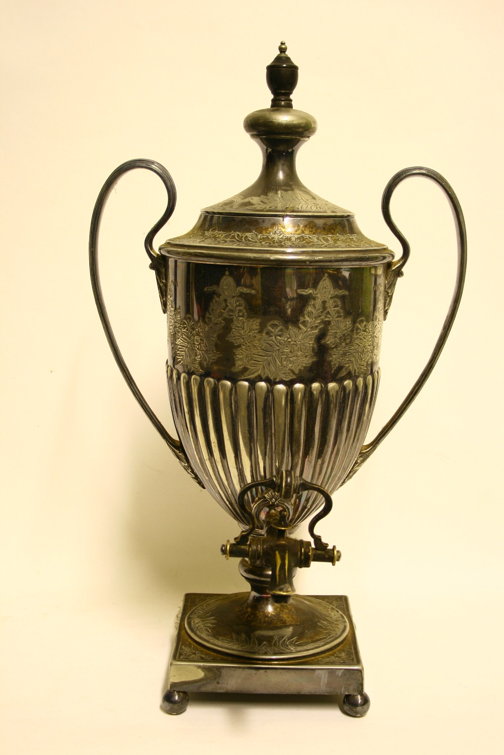 A semi-fluted vase shaped tea urn with engraved floral decoration, reeded loop handles, &on square