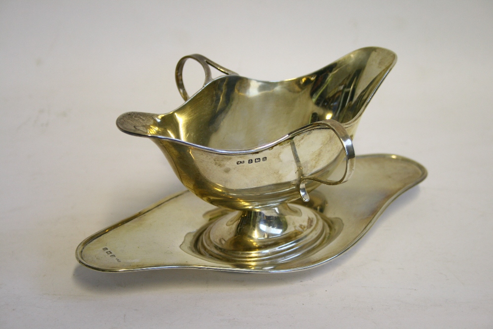 An Edwardian oval double-lipped sauce boat with loop handles & on separate stand, 6½" wide;