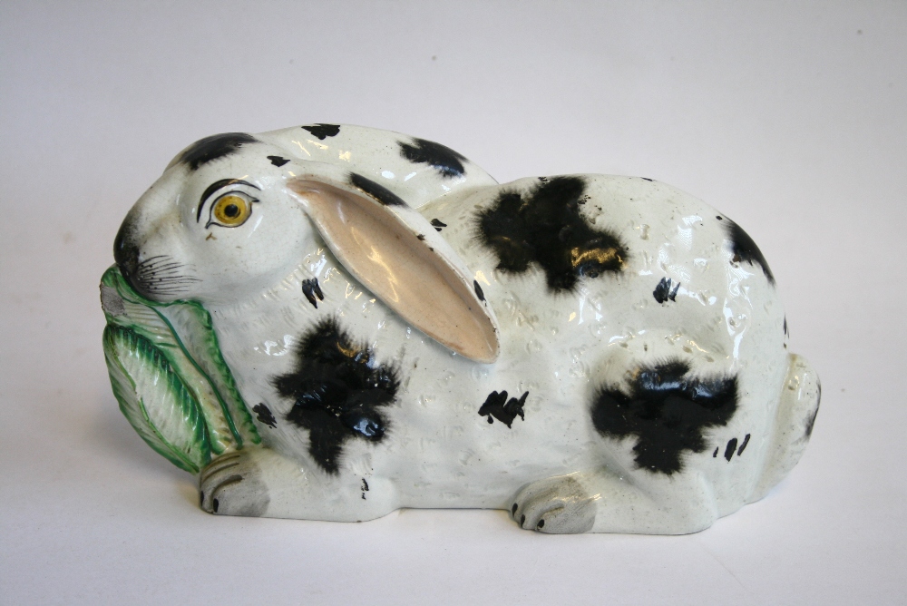 A VICTORIAN STAFFORDSHIRE POTTERY MODEL OF A RABBIT in crouching pose, eating a Cos lettuce leaf,