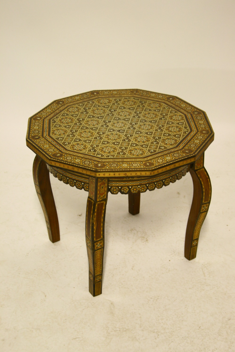 A Damascus twelve-sided low occasional table with finely inlaid all-over geometric design; 22" wide.