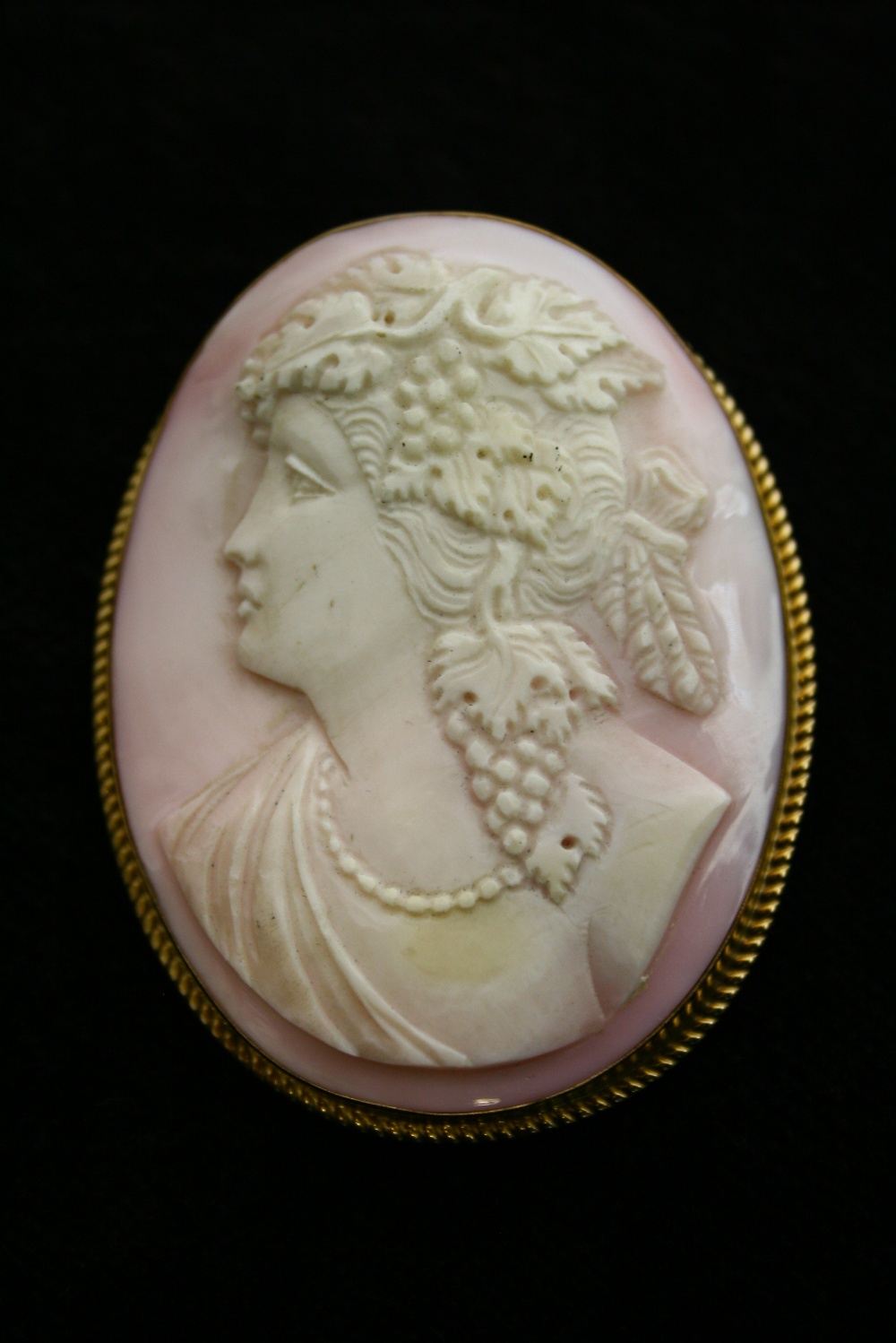 A large oval carved shell pink-ground cameo brooch depicting a classical female bust, in 9ct. gold