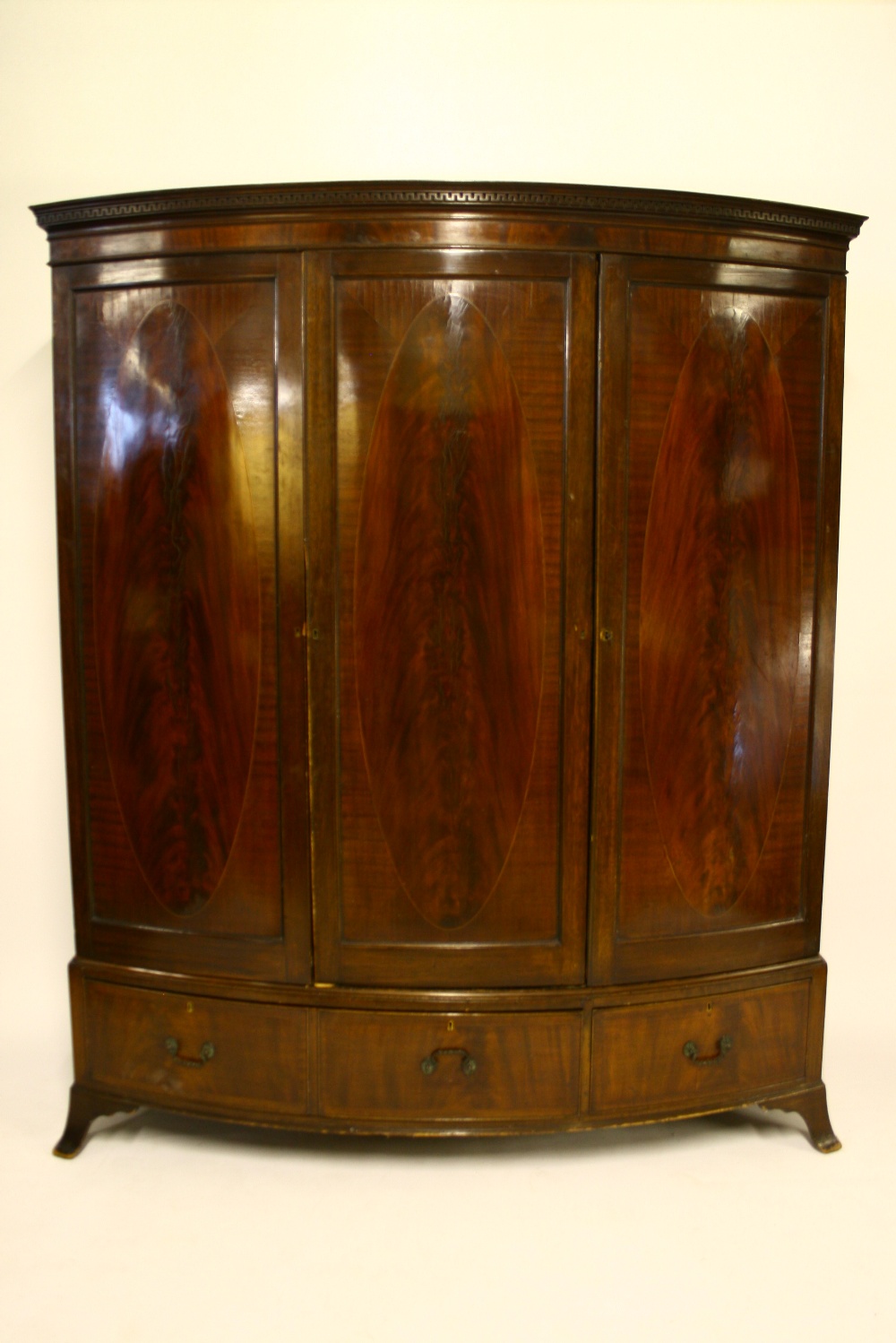 AN INLAID-MAHOGANY BOW-FRONT WARDROBE having dentil cornice, fitted four sliding trays & two drawers