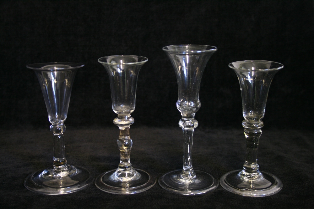 Four 18th century small drinking glasses, each with bell or trumpet-shaped bowl, on plain knopped