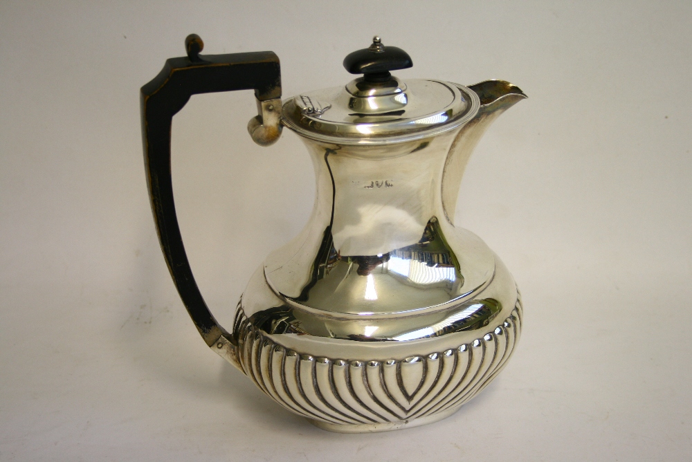A late Victorian hot-water jug of oblong semi-fluted form, with hinged cover & ebonised wood handle,