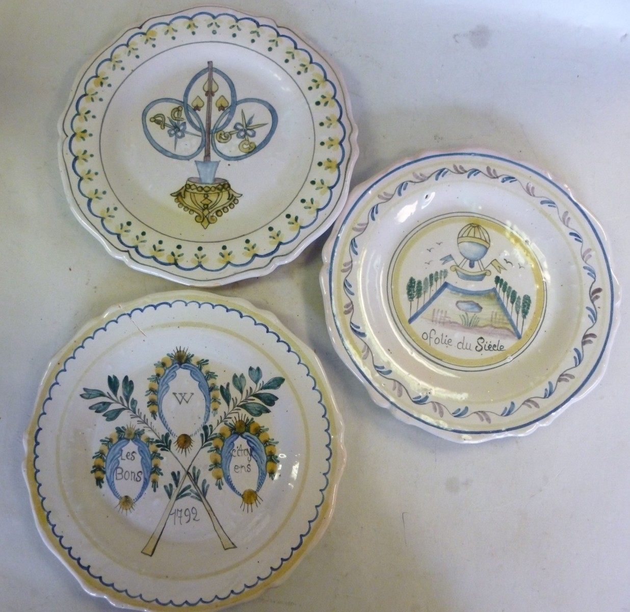 Three similar Continental faience pottery wavy edged plates, each variously decorated in tones of