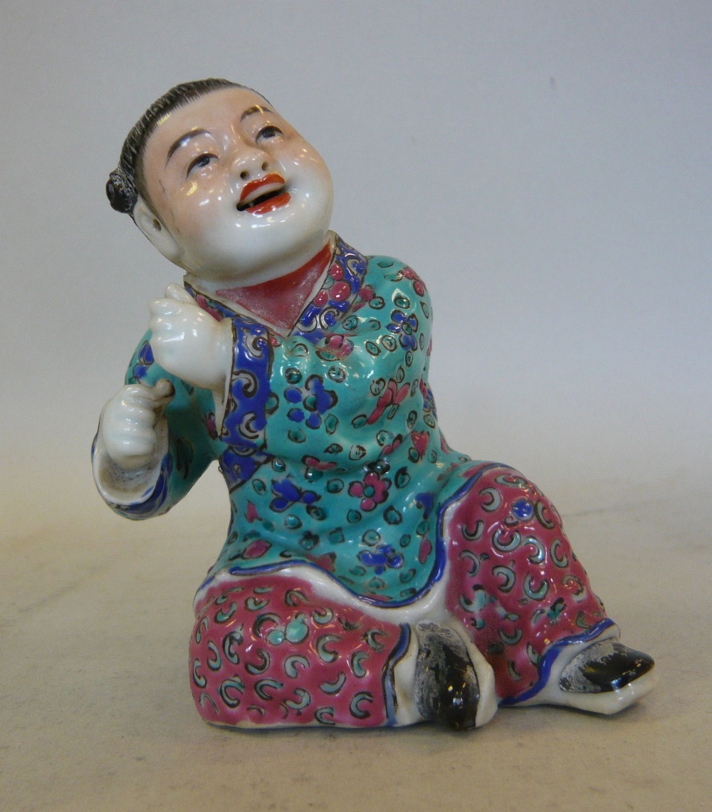 An early 20thC Chinese famille rose porcelain figure, a seated boy 4``h