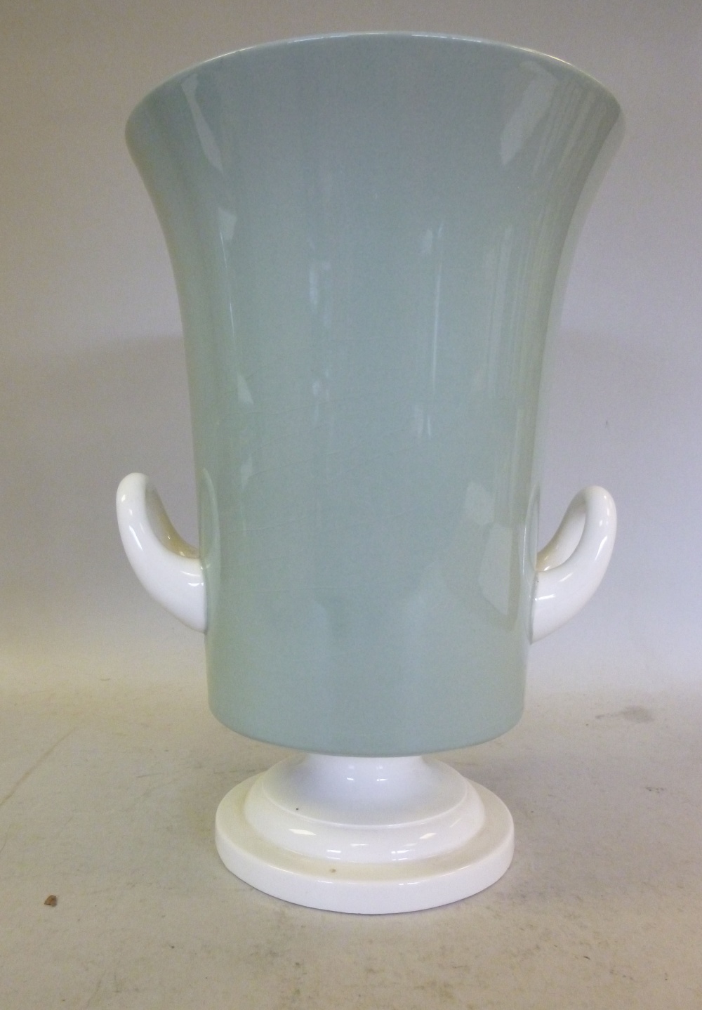 A Keith Murray Wedgwood celadon and ivory glazed pottery vase of tapered form with opposing loop