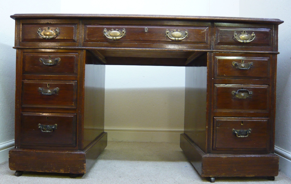 A late Victorian mahogany desk, having a gilded tooled, red hide scriber, over three in-line drawers