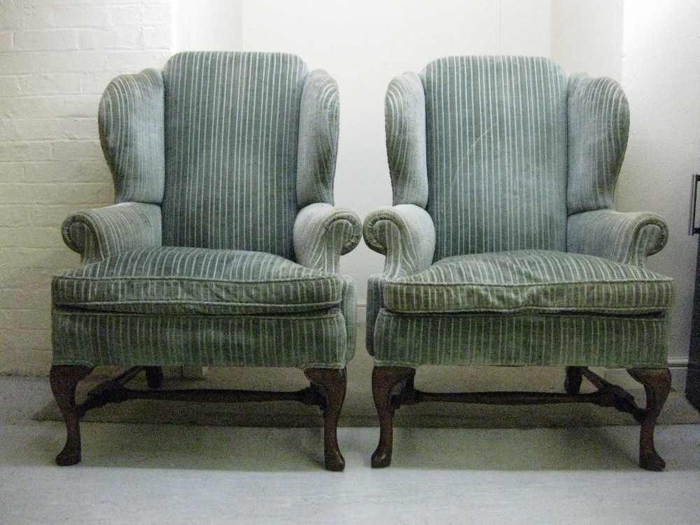 A pair of Georgian design wingback armchairs, having scrolled arms, upholstered in green striped