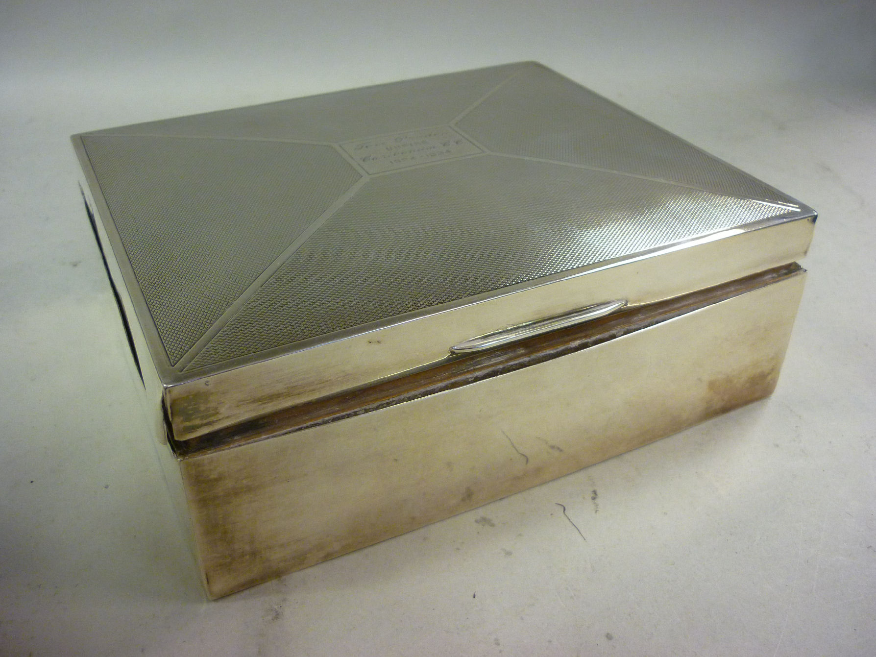 A silver cigarette box, having straight sides and a domed, engine turned, hinged lid, enclosing a