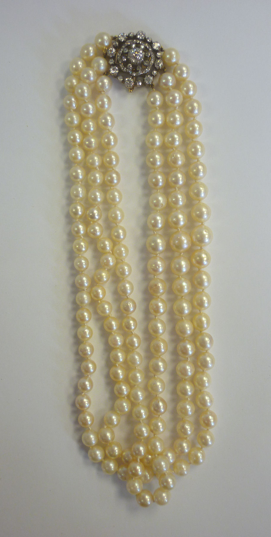 A three row cultured pearl necklace, the gold framed cluster clasp with a safety bar, set with old