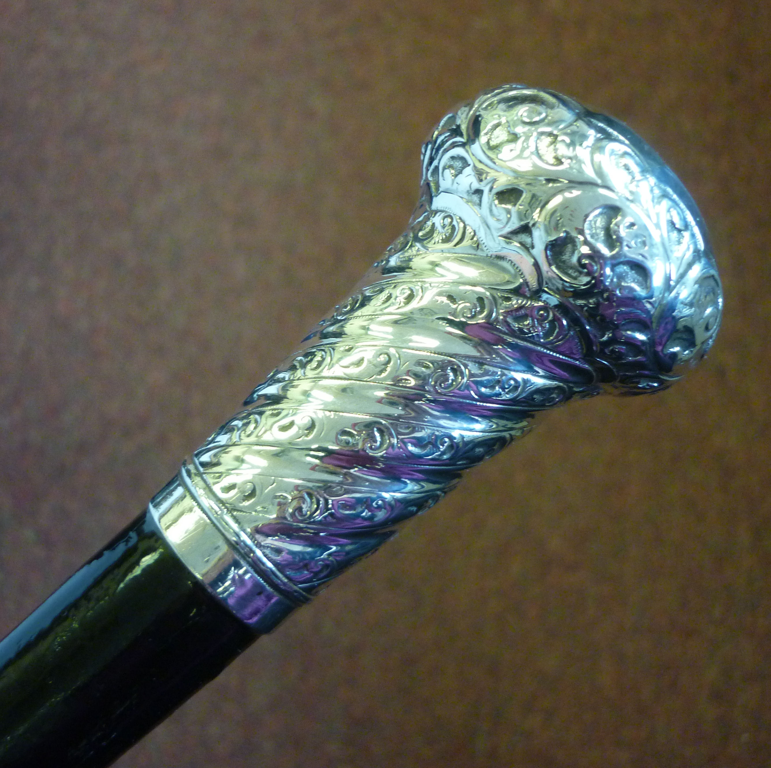 A walking cane, the tapered, black lacquered shaft with a silver cap terminal and spiral moulded,