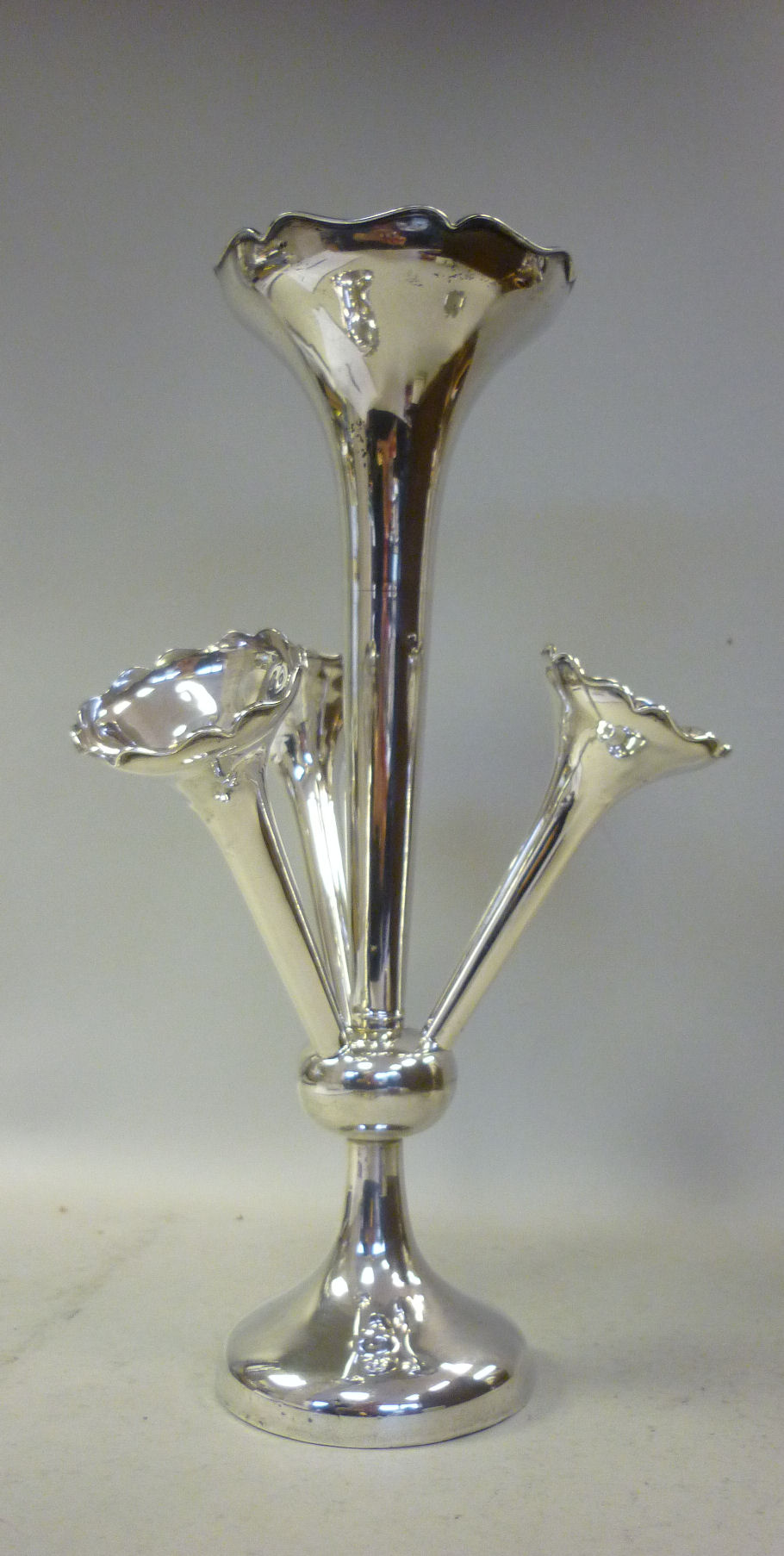 A silver epergne, having a central trumpet shaped vase with a wavy rim, above three subsidiary