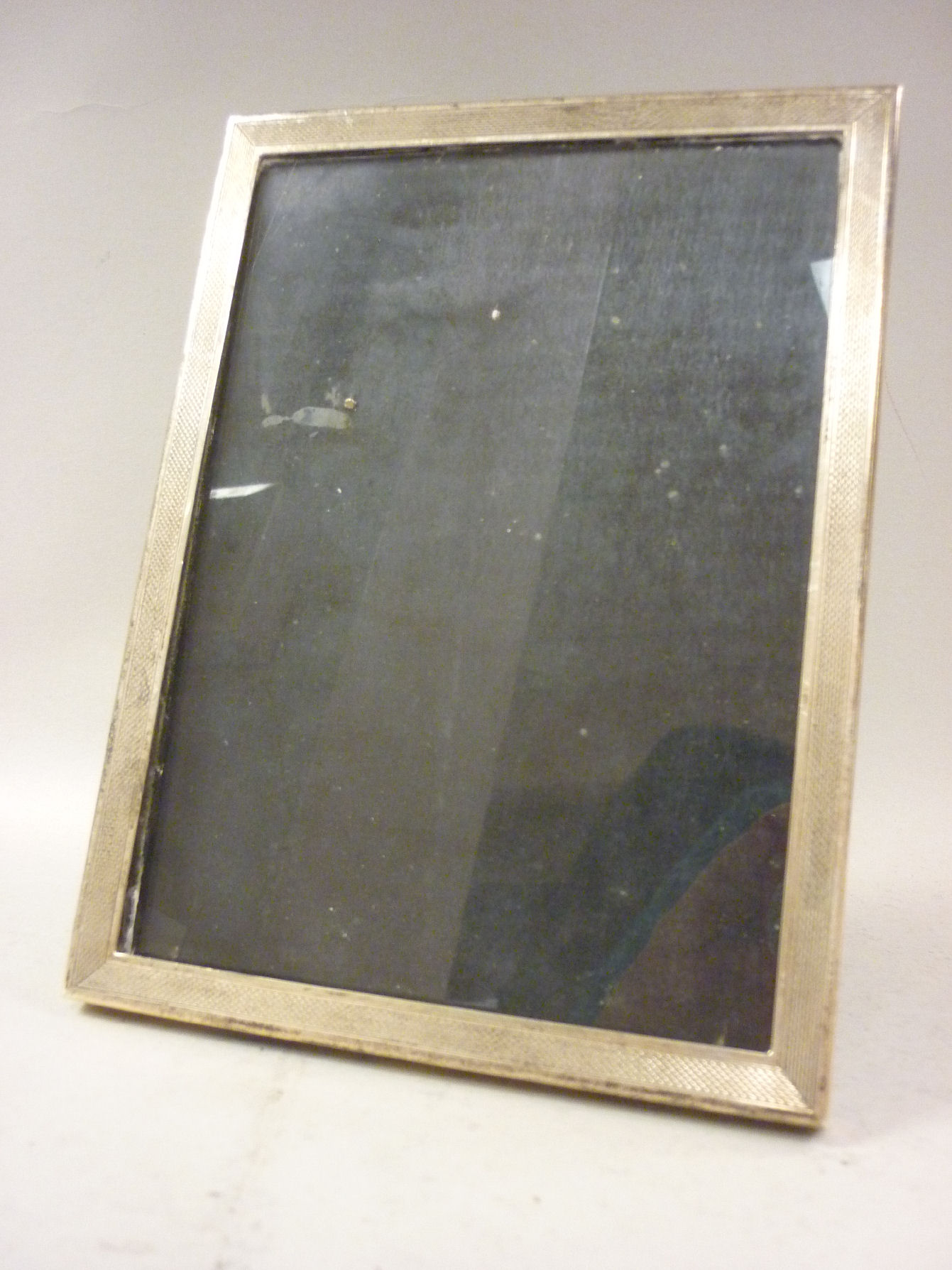 A glazed silver photograph frame with engine turned decoration, on an ebonised back and an easel