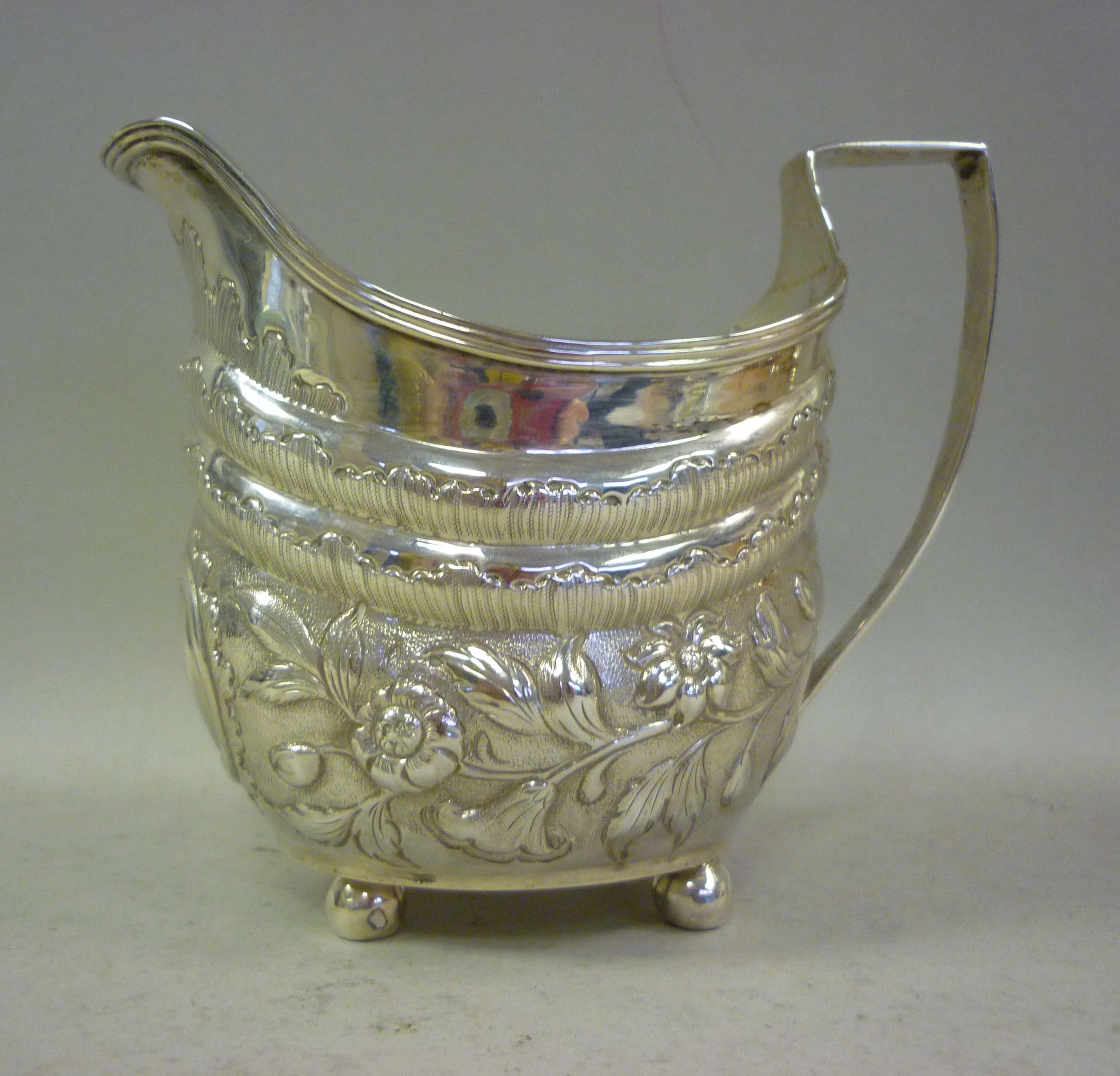 A George III silver cream jug of oval, double ogee form with an applied wire rim, an angular loop