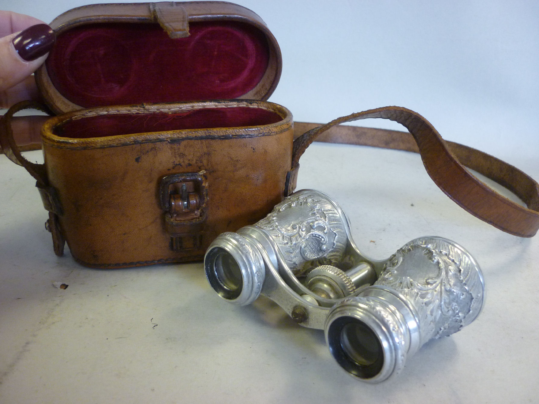 A pair of late 19thC polished alloy opera glasses with foliate scroll cast ornament to the