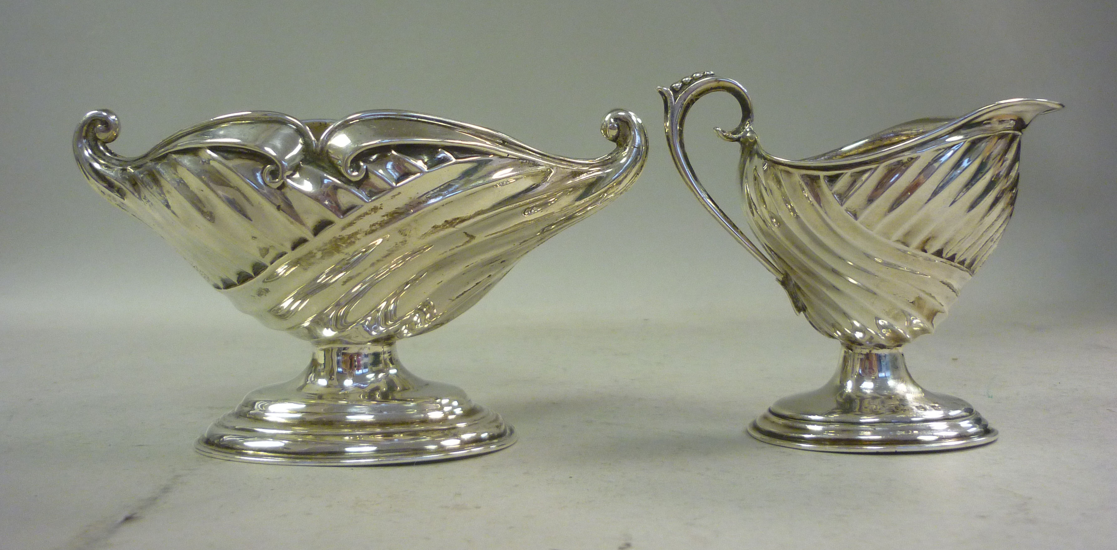A late Victorian silver cream jug of wrythen fluted pedestal design and a matching sugar basin H