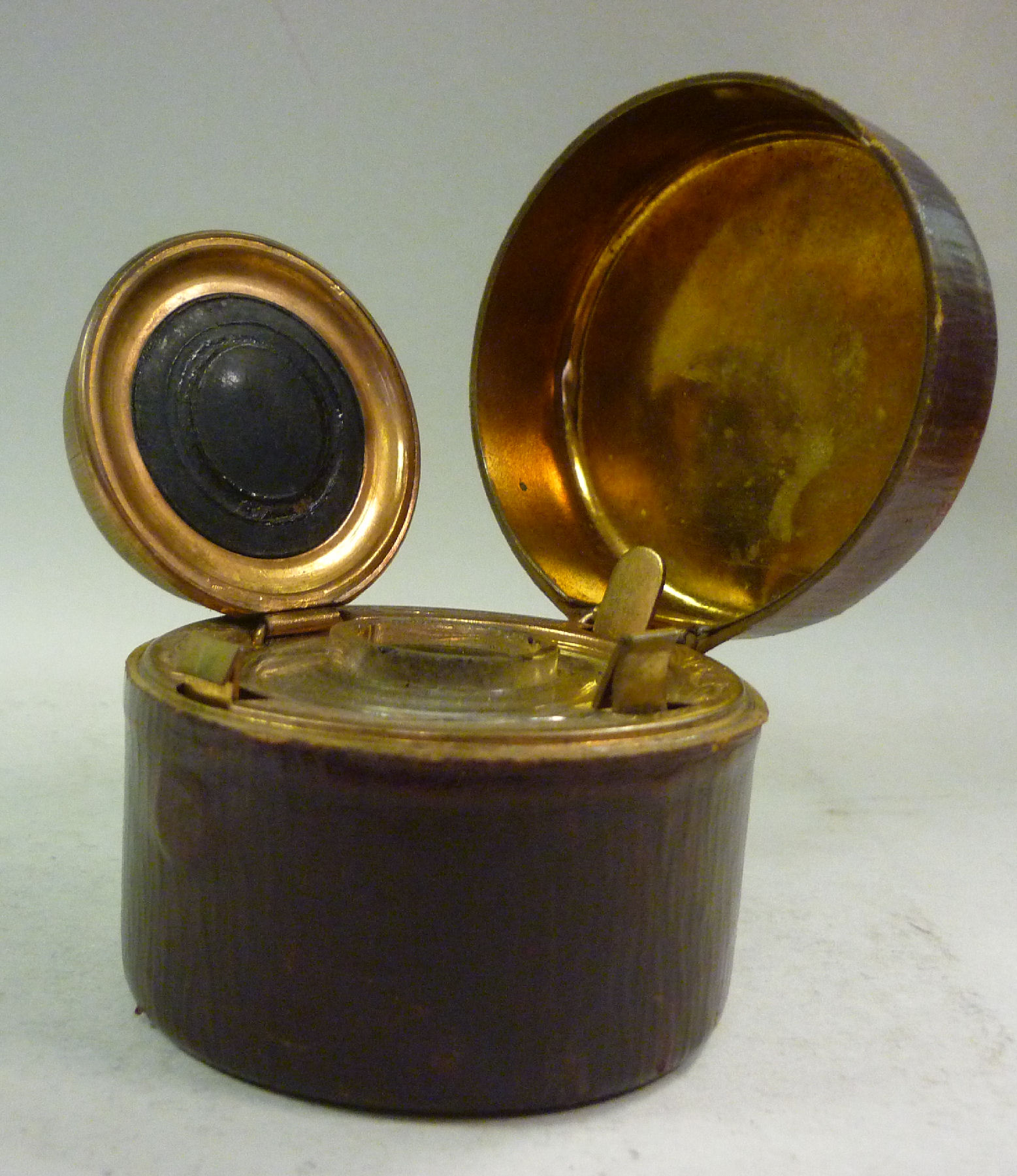 A late Victorian traveller`s hide covered inkwell of drum design, the hinged cap, on a button clasp,
