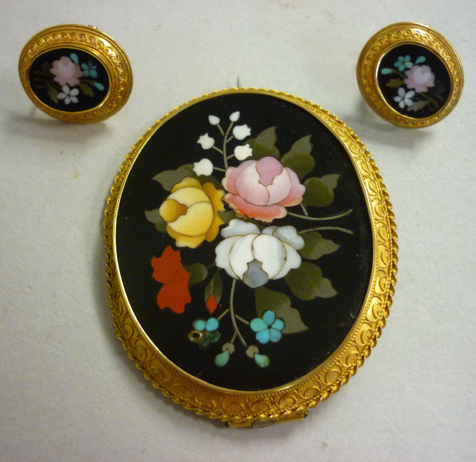A 9ct overlaid wireworked oval framed brooch, set with an inlaid floral hardstone tablet with a pair