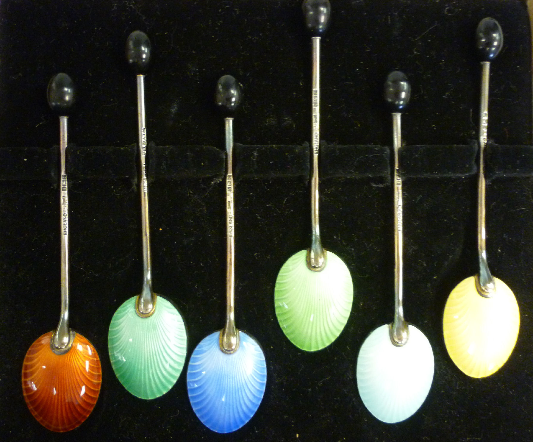 A set of six silver bean terminal coffee spoons with individually coloured, engine turned enamel