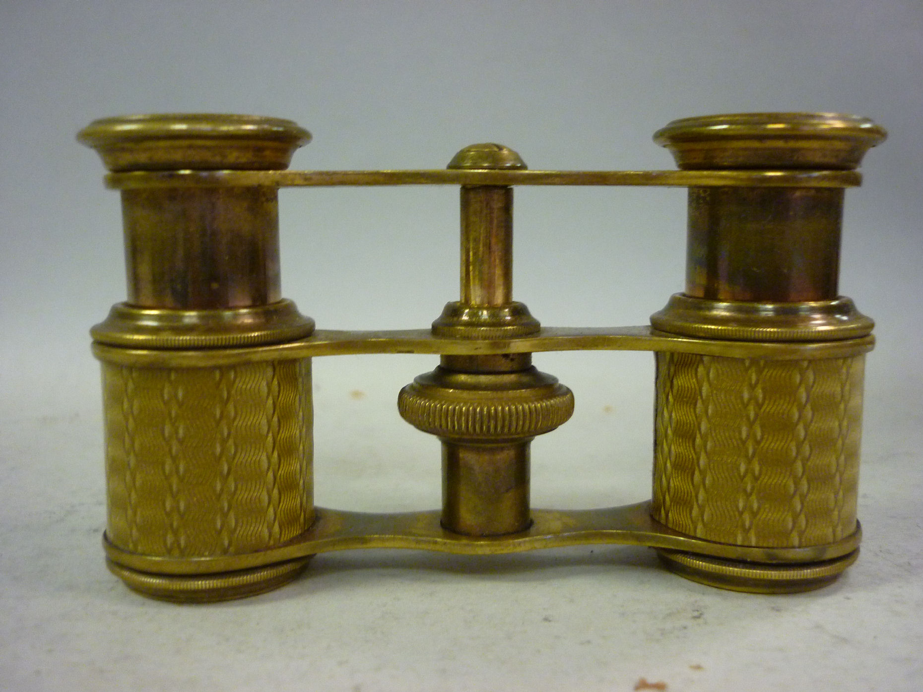 A pair of late 19thC French lacquered brass opera glasses with straight, gilt coloured, engine