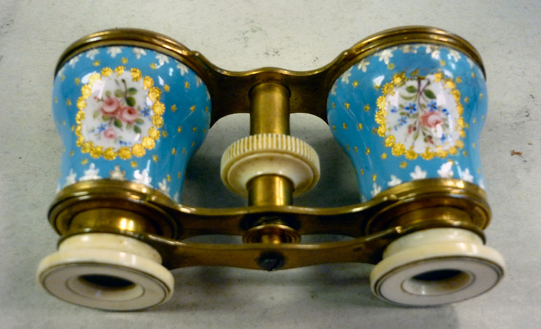 A pair of late 19thC French gilt metal opera glasses with turned ivory eyepiece surrounds, the