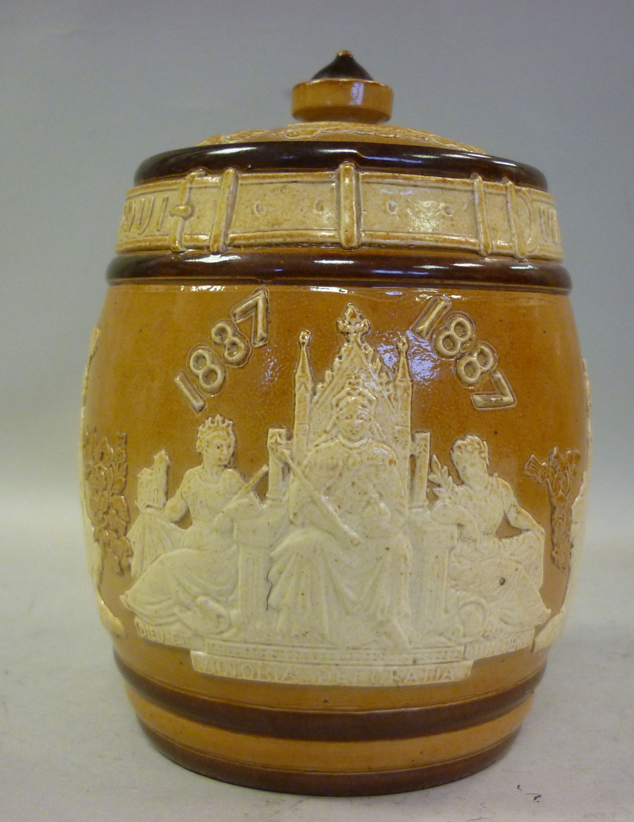 A Doulton Lambeth two tone brown glazed stoneware barrel design tobacco jar and lid, decorated in