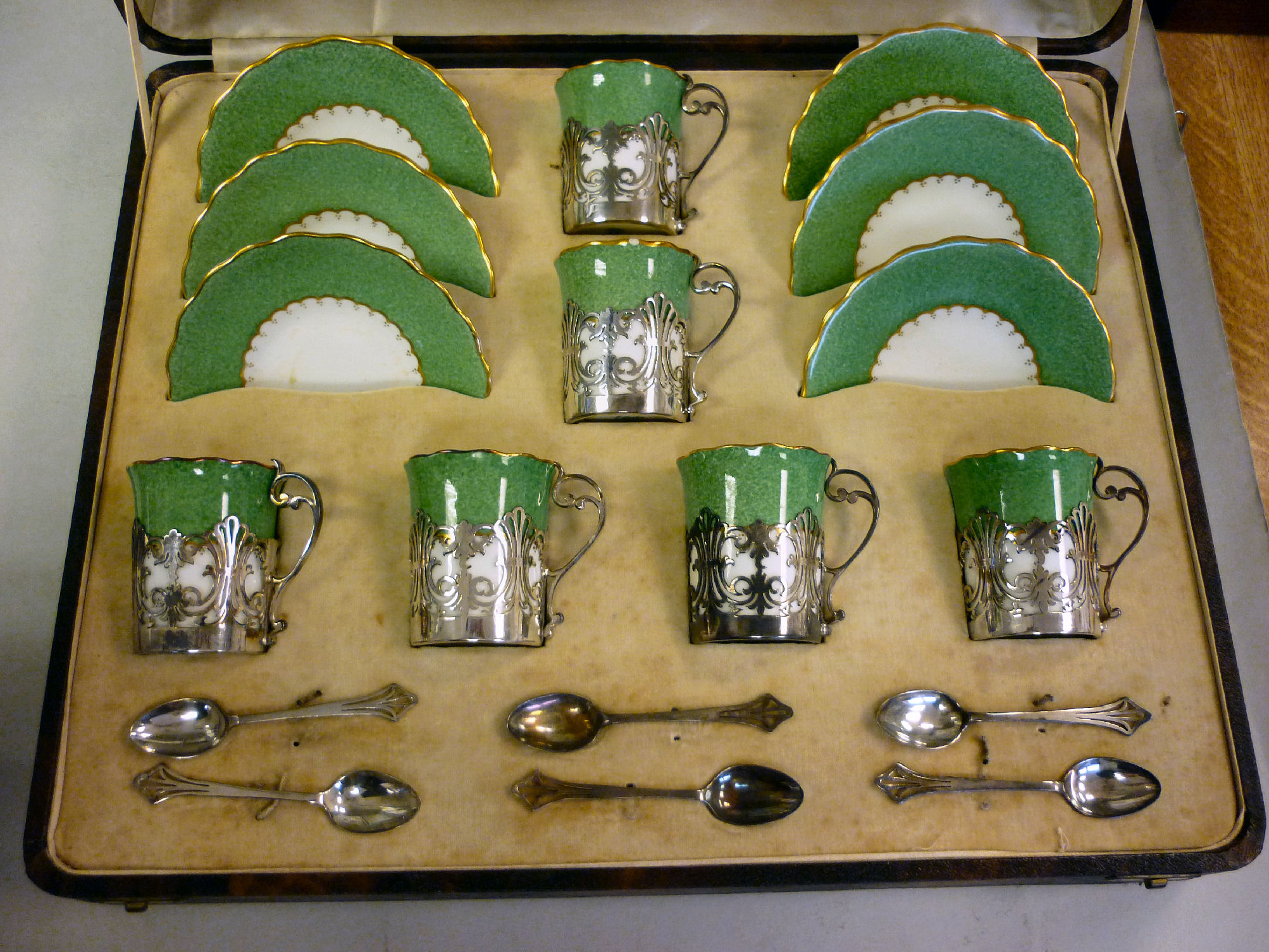 A set of six Coalport sponged green glazed and gilded china coffee cans and saucers, set in finely