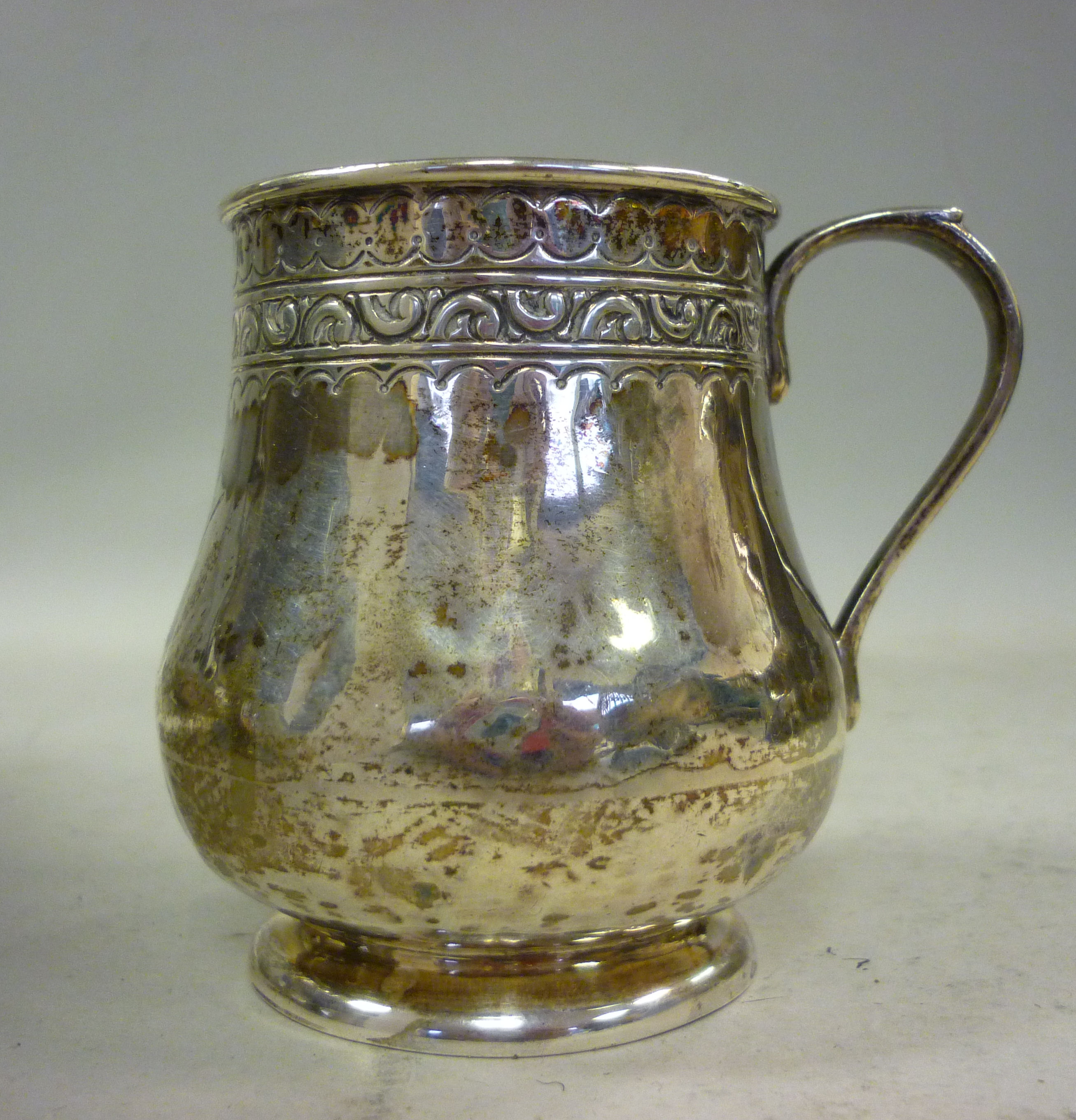 A silver small baluster shaped tankard, having a decoratively cast and applied wire rim and a loop