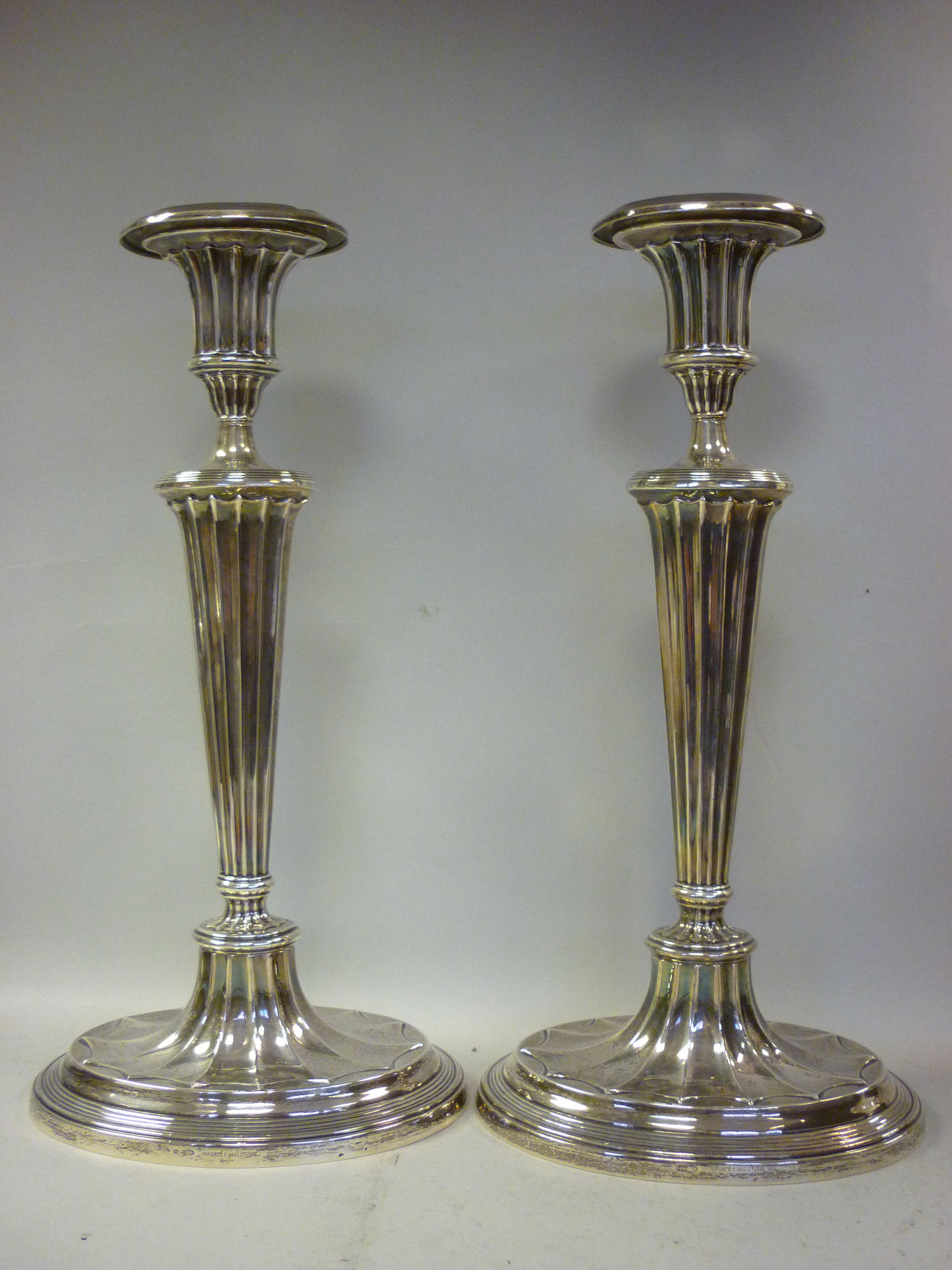 A pair of loaded silver candlesticks of oval outline, each having a vase shaped socket and a