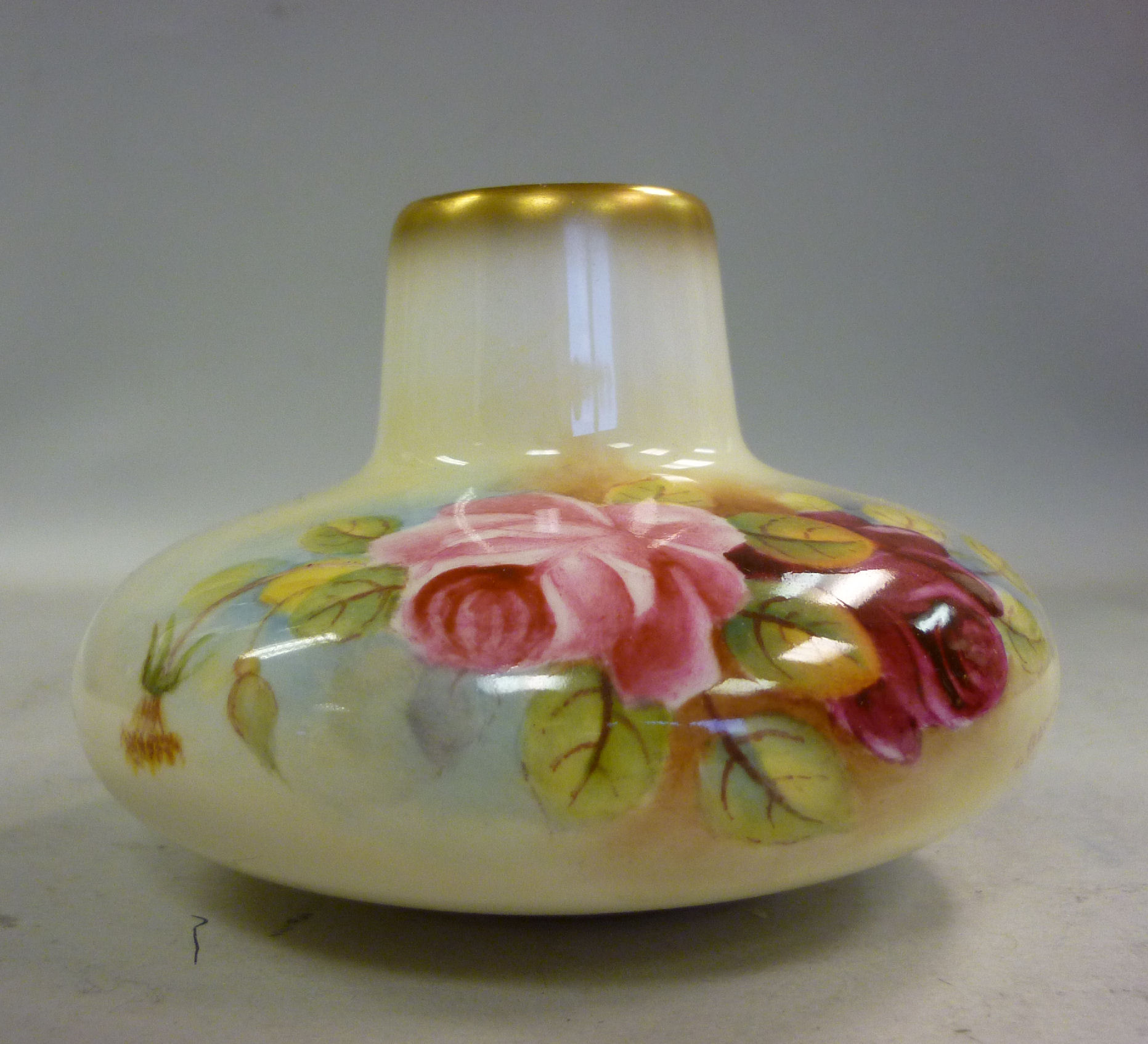 A Royal Worcester ivory glazed china vase of squat, bulbous form, decorated with roses and gilding